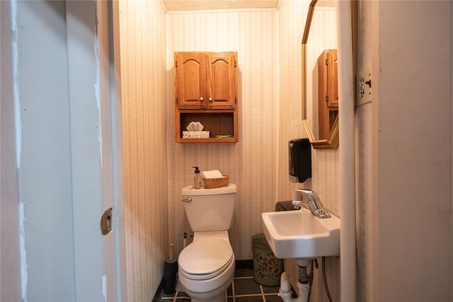 bathroom with toilet, sink, and tile patterned flooring