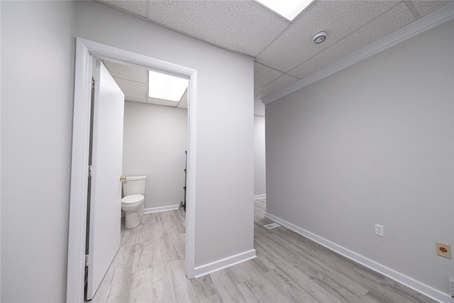 bathroom featuring a drop ceiling, hardwood / wood-style flooring, and toilet