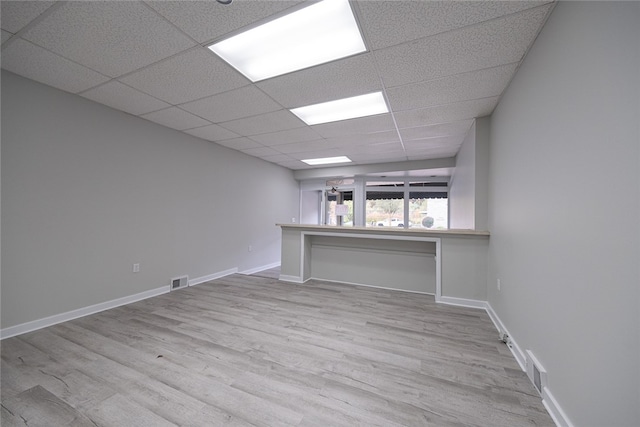 spare room with a drop ceiling and light wood-type flooring