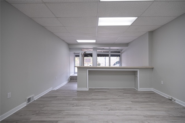 unfurnished living room featuring light hardwood / wood-style flooring and a paneled ceiling