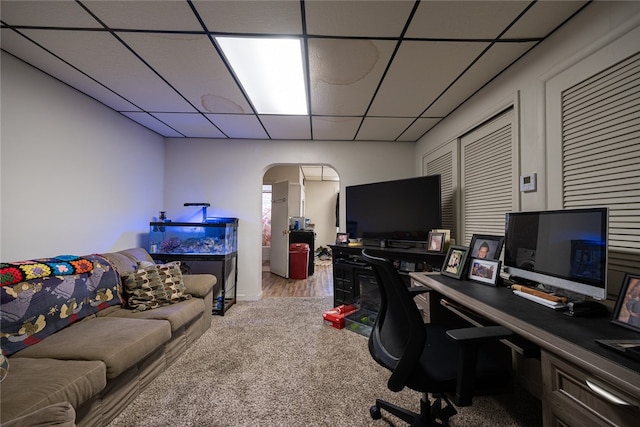 carpeted home office with a drop ceiling