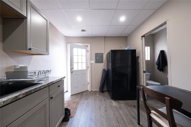 kitchen featuring gray cabinets, a paneled ceiling, light hardwood / wood-style floors, and black fridge