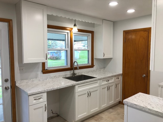 kitchen featuring white cabinetry, light stone countertops, and sink