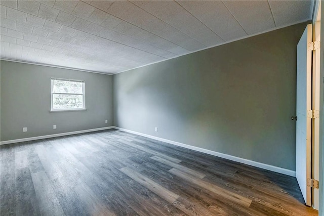 empty room featuring crown molding, baseboards, and dark wood finished floors