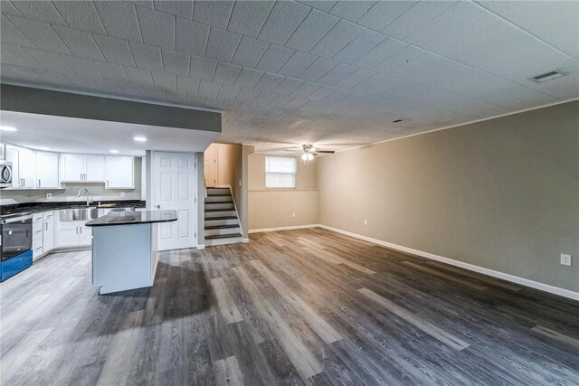 kitchen with dark countertops, open floor plan, stove, and dark wood-type flooring