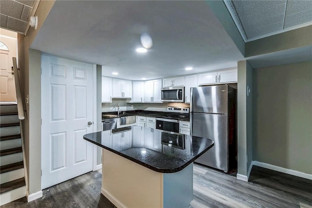 kitchen featuring appliances with stainless steel finishes, dark wood-style flooring, white cabinetry, and baseboards