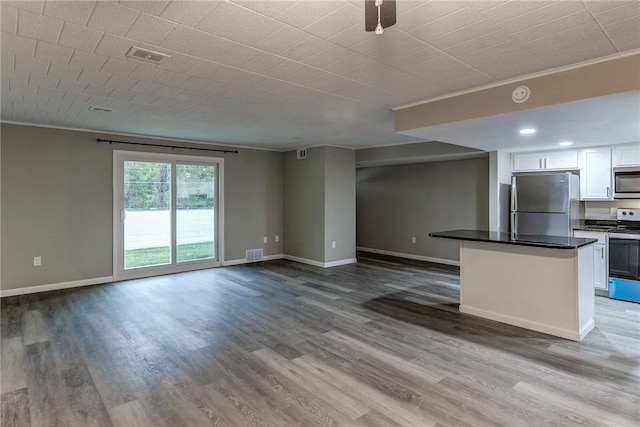 unfurnished living room with baseboards, visible vents, wood finished floors, and crown molding