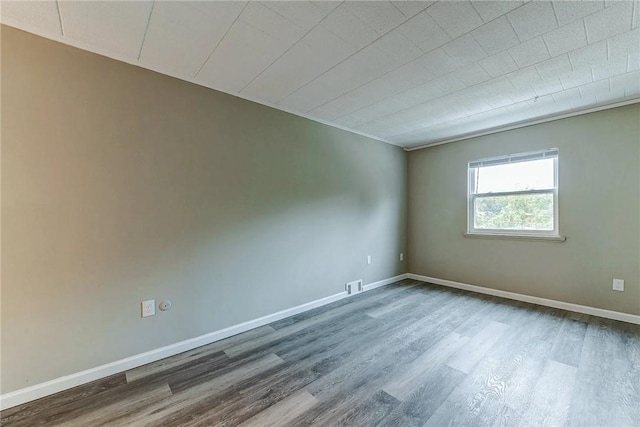 empty room featuring baseboards, visible vents, and wood finished floors