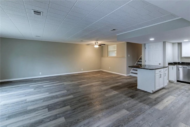 kitchen with white cabinetry, dark countertops, baseboards, dishwasher, and dark wood finished floors