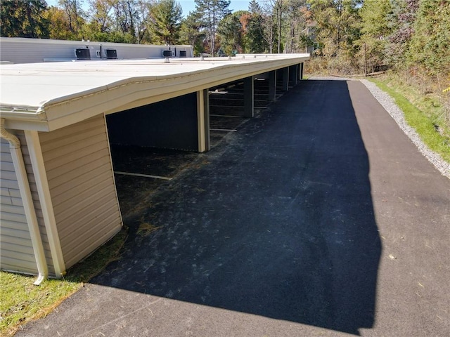 exterior space featuring gutters, a flat roof, a downspout, and an exterior structure