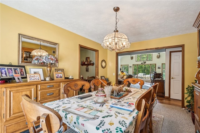 dining room featuring a notable chandelier, a textured ceiling, and wood-type flooring