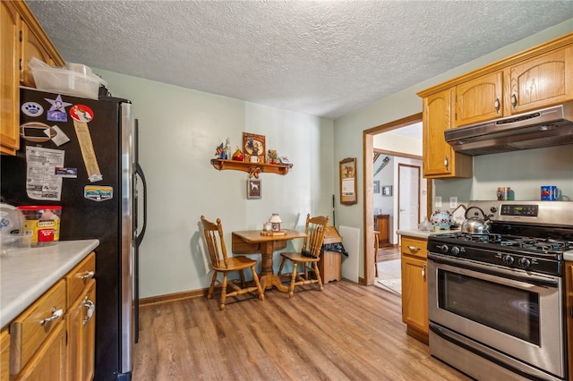 kitchen with appliances with stainless steel finishes, a textured ceiling, and light wood-type flooring