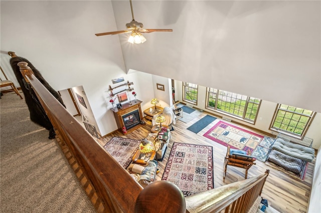 living room featuring ceiling fan, hardwood / wood-style flooring, and a towering ceiling