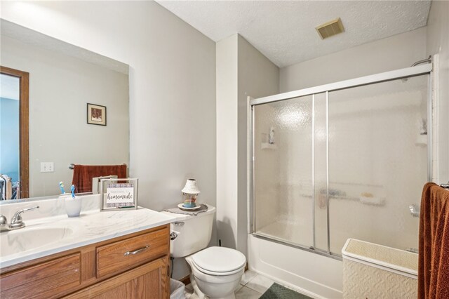 full bathroom featuring a textured ceiling, toilet, bath / shower combo with glass door, vanity, and tile patterned flooring