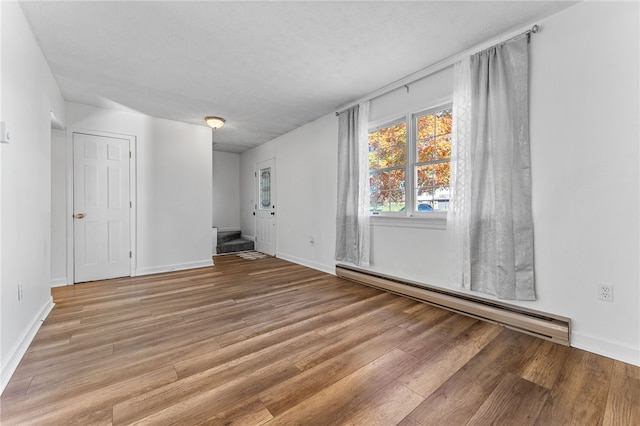 unfurnished room featuring light hardwood / wood-style flooring, a textured ceiling, and a baseboard radiator