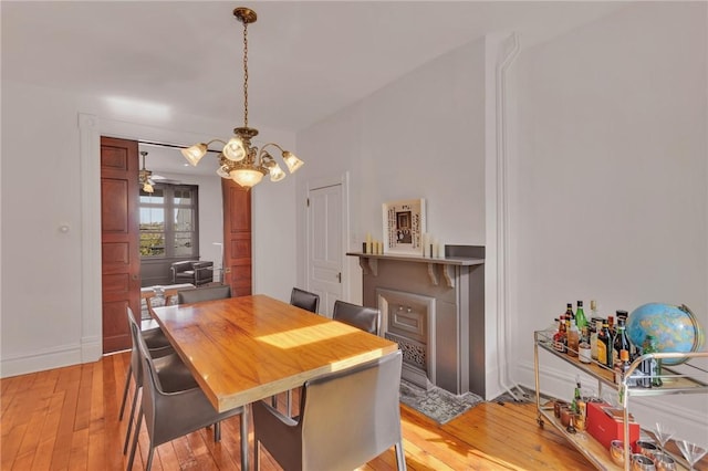 110 Pius St, South Side, PA 15203 - dining room featuring light wood-type flooring, a chandelier, a fireplace with flush hearth, and baseboards
