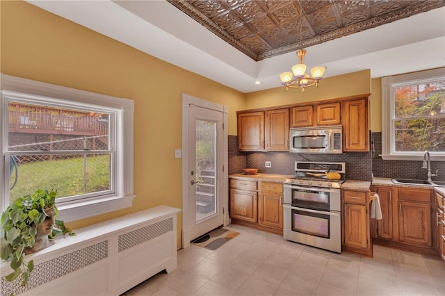 110 Pius St, South Side, PA 15203 - kitchen with stainless steel appliances, a sink, brown cabinetry, an ornate ceiling, and radiator