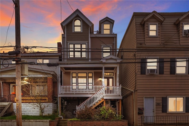 back house at dusk featuring covered porch