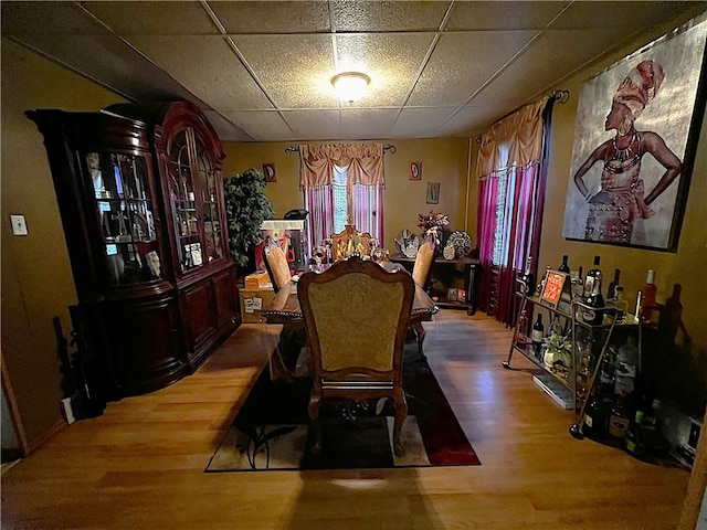 dining space with a paneled ceiling and hardwood / wood-style flooring