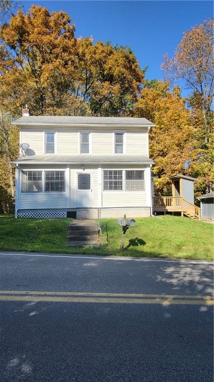 front of property with a sunroom and a front yard