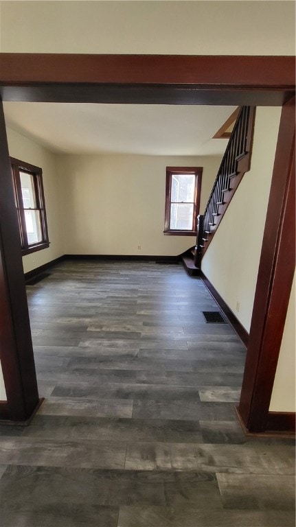 empty room featuring a healthy amount of sunlight and dark wood-type flooring