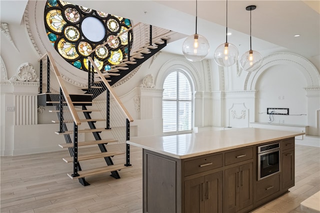 kitchen with light hardwood / wood-style floors, dark brown cabinets, and pendant lighting