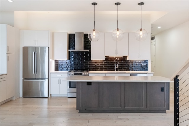 kitchen with wall chimney exhaust hood, sink, a center island, white cabinetry, and appliances with stainless steel finishes