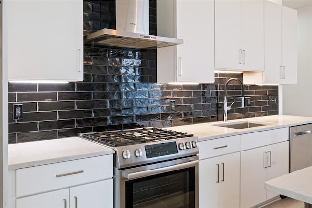 kitchen featuring wall chimney exhaust hood, sink, appliances with stainless steel finishes, and white cabinets