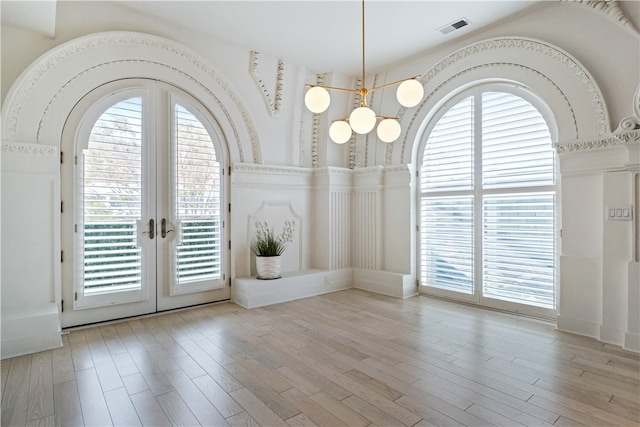 unfurnished dining area with french doors, light hardwood / wood-style floors, and a healthy amount of sunlight