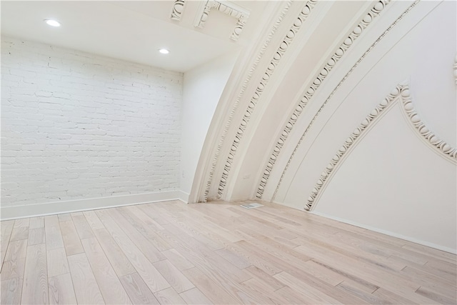 unfurnished bedroom with brick wall and light hardwood / wood-style floors