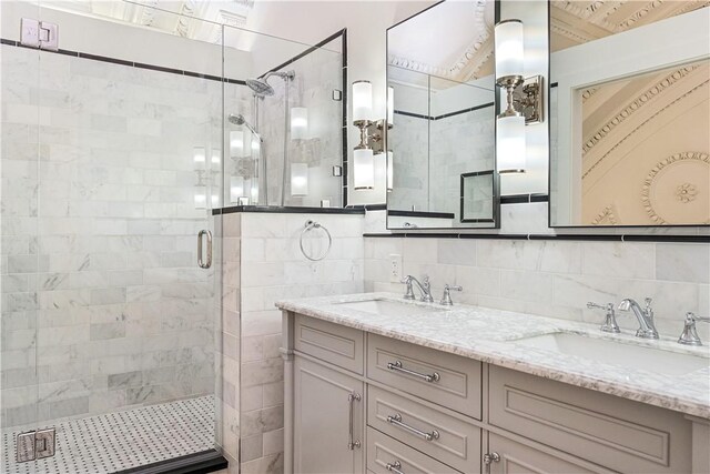 bathroom with a shower with door, vanity, decorative backsplash, and tile walls