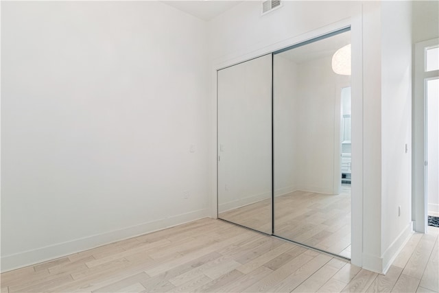 unfurnished bedroom featuring a closet and light wood-type flooring