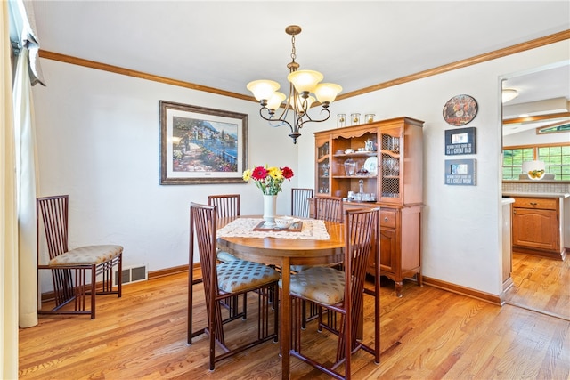 dining area featuring ornamental molding, a chandelier, and light wood-type flooring