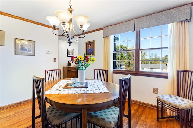 dining space featuring wood-type flooring, ornamental molding, and an inviting chandelier