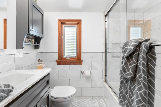 bathroom featuring toilet, tile patterned floors, walk in shower, tile walls, and vanity