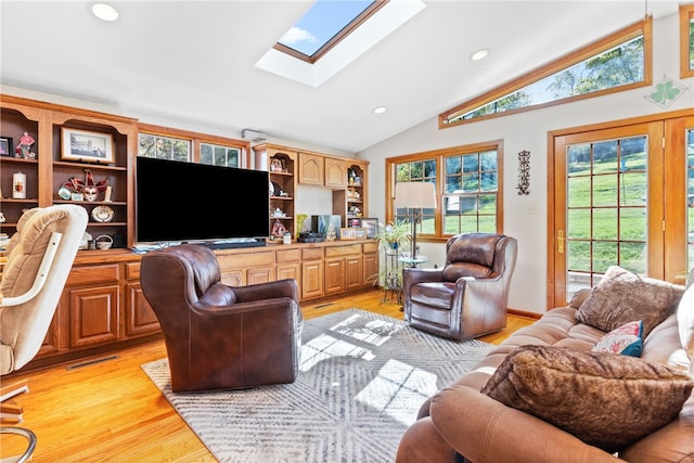 living room featuring light hardwood / wood-style flooring, high vaulted ceiling, and a skylight