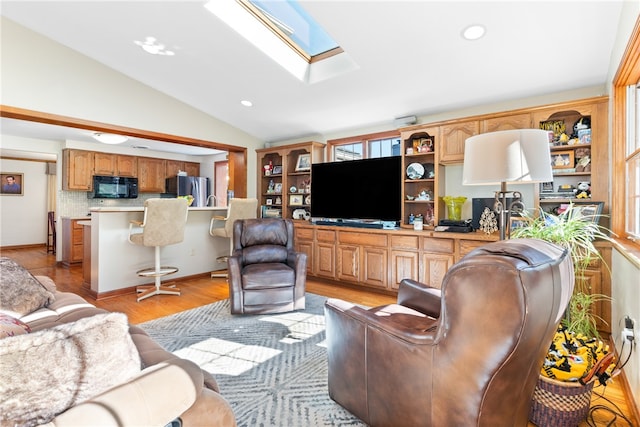 living room with light hardwood / wood-style floors and vaulted ceiling with skylight