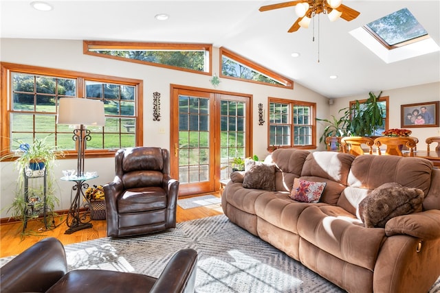 living room with light hardwood / wood-style floors, lofted ceiling with skylight, and ceiling fan