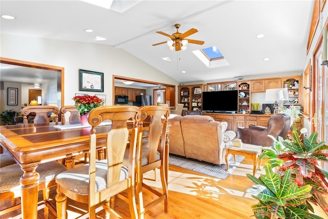 dining room with light hardwood / wood-style floors, vaulted ceiling with skylight, and ceiling fan