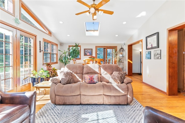 living room with lofted ceiling with skylight, light wood-type flooring, and ceiling fan