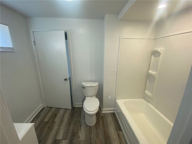 bathroom featuring hardwood / wood-style flooring, toilet, and bathing tub / shower combination