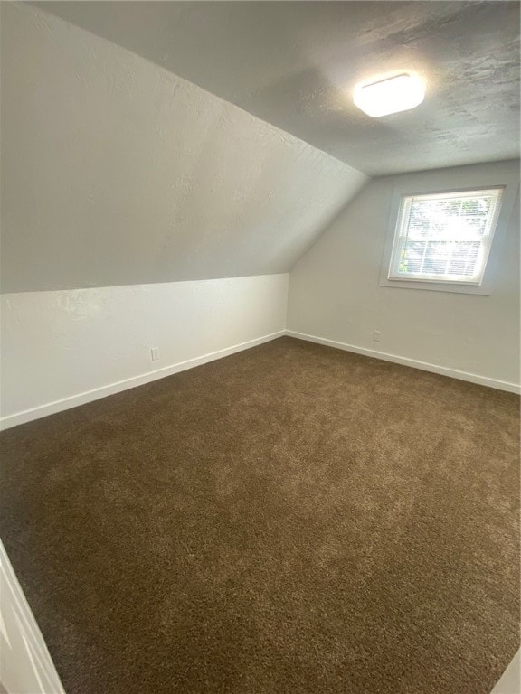 bonus room with dark colored carpet, a textured ceiling, and lofted ceiling