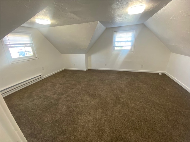 additional living space featuring a textured ceiling, baseboard heating, and a healthy amount of sunlight