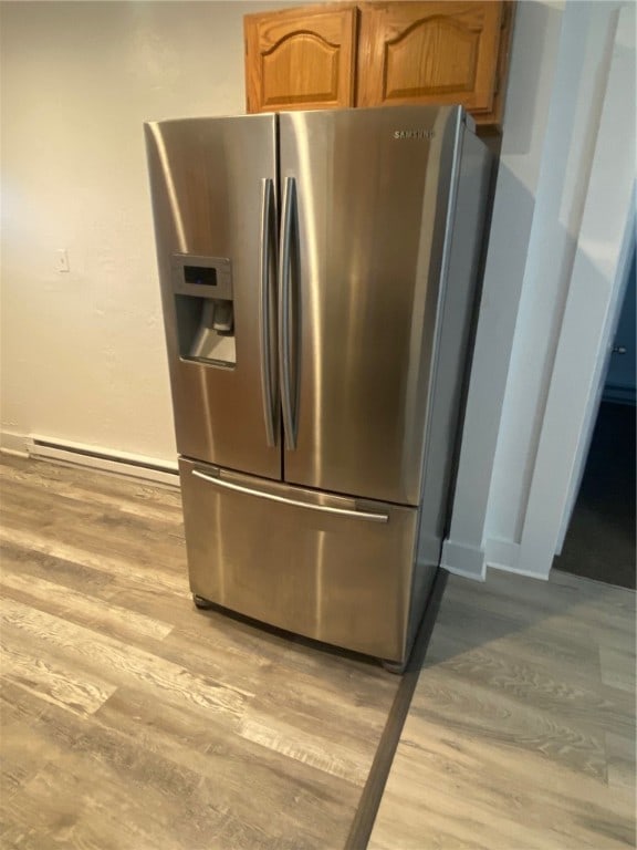 interior details with stainless steel refrigerator with ice dispenser, a baseboard radiator, and light wood-type flooring