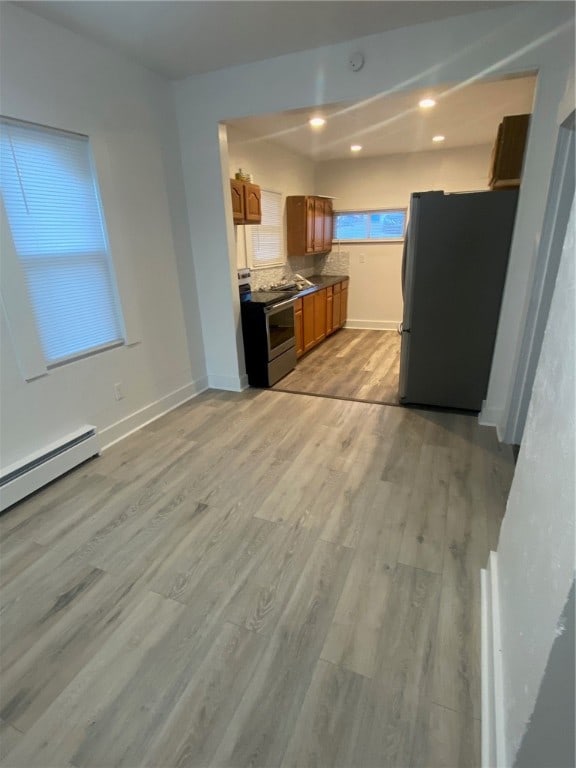 kitchen with stainless steel appliances, light hardwood / wood-style floors, and a baseboard radiator