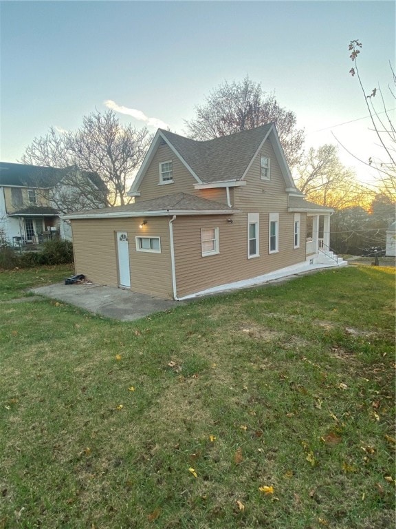 property exterior at dusk with a lawn and a patio area