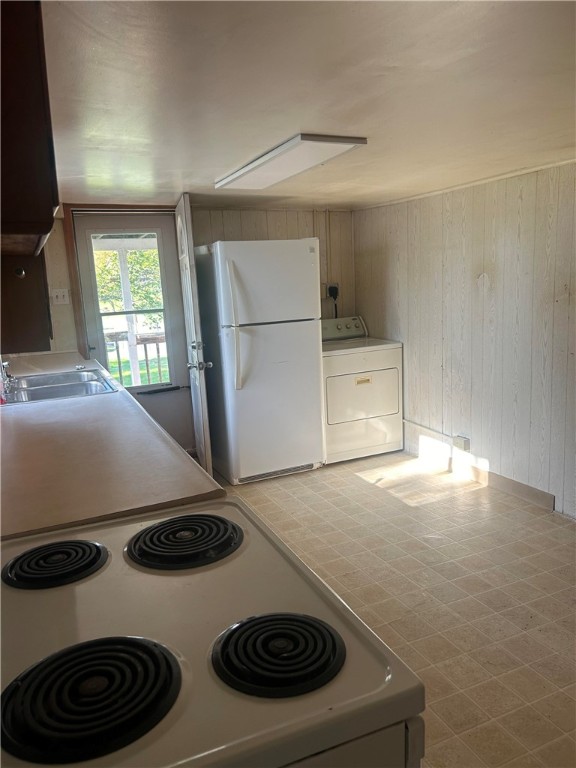 kitchen with washer / dryer, sink, and white appliances