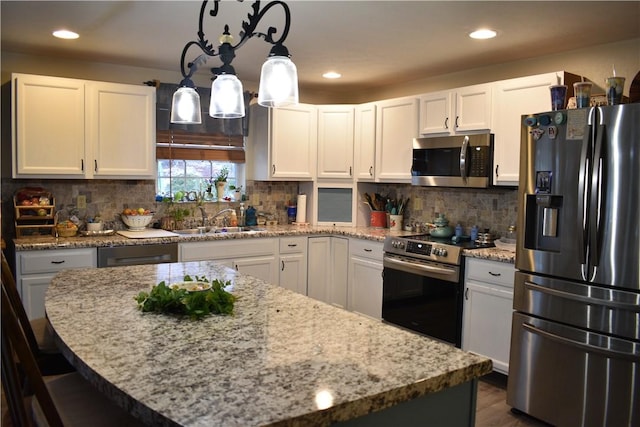 kitchen featuring sink, white cabinets, decorative light fixtures, and appliances with stainless steel finishes