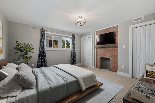 bedroom featuring light colored carpet and a brick fireplace