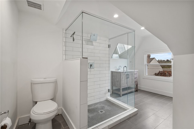 bathroom with a tile shower, toilet, tile patterned flooring, and vanity